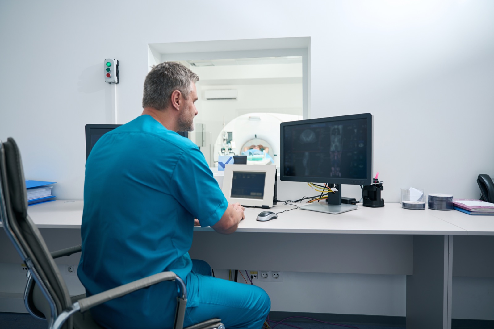 A radiologist in scrubs reporting at a workstation